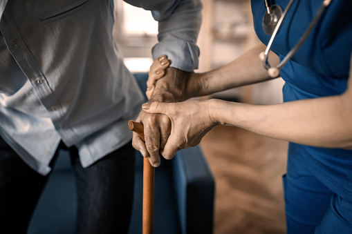 Medical worker helping older man with cane
