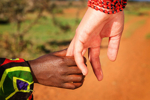 white woman holding an African child's hand