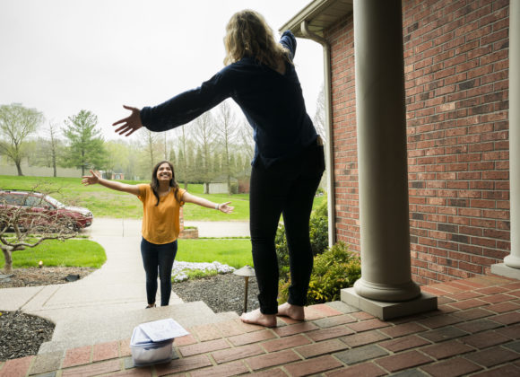 Two women greeting each other while social distancing